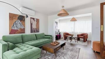 Un salon moderne avec un canapé vert, une table basse en bois et un coin repas comprenant deux chaises.