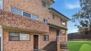 A two-story brick building with a front entrance, a small set of stairs leading to the door, and a well-maintained lawn. - Linton, Architect Home Near Mt Panorama (Kelso)