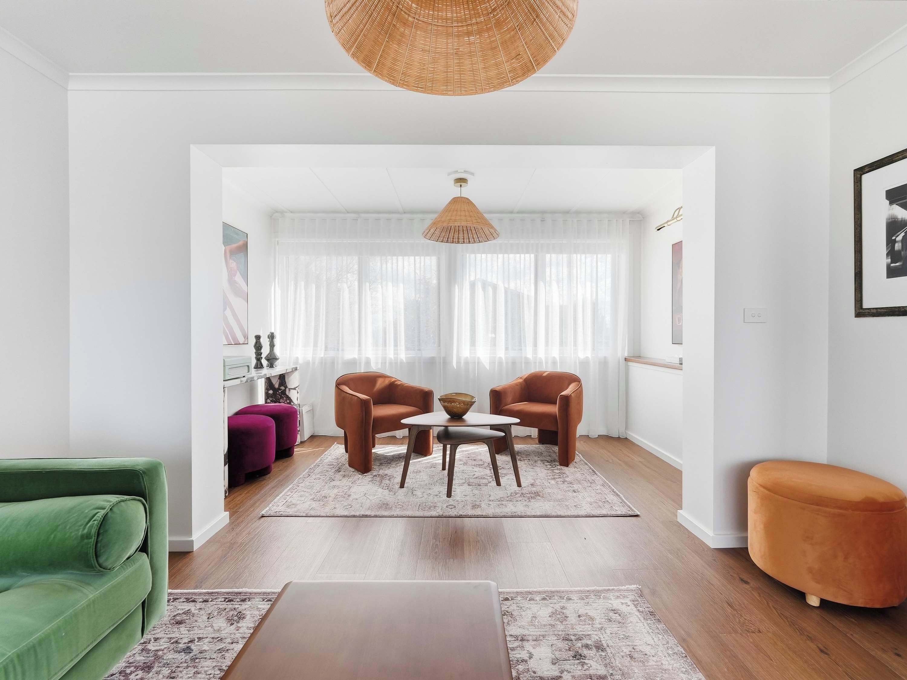 A modern living room with a sofa, chairs, a coffee table, and a hanging light fixture.