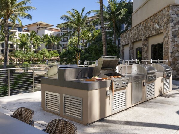 Een buitenkeuken met een barbecue en zitplaatsen.