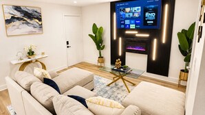 Ein modernes Wohnzimmer mit einem beigefarbenen Ecksofa, einem Glastisch und einem flachbildfernseher an der Wand.