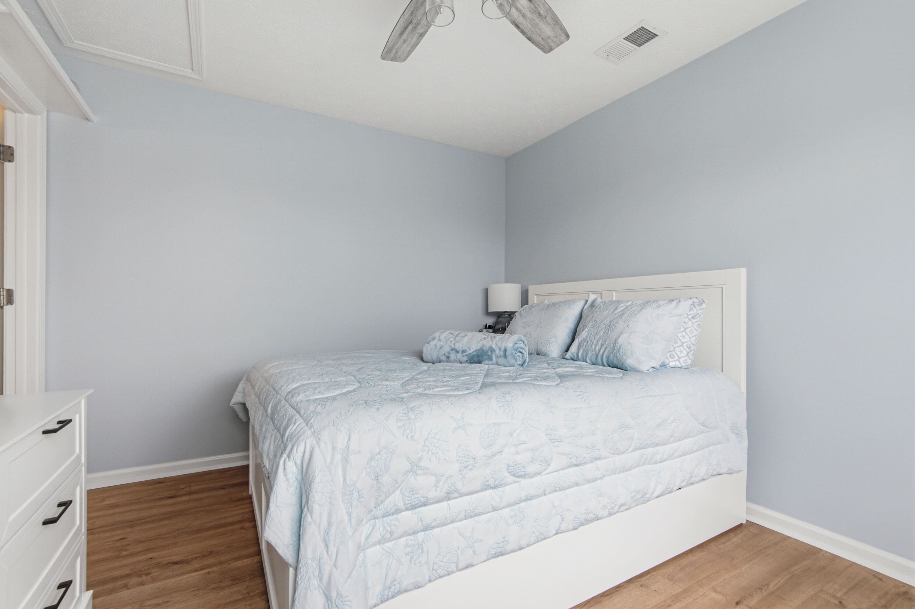 A bedroom with a bed, a nightstand, and a dresser.