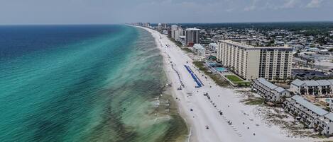 A coastal cityscape with a beach, hotels, and a clear sky.