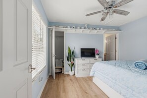 A bedroom with a bed, a television, a ceiling fan, and a walk-in closet. - So Cute! WALK to Beach Close to Restaurants Marina & State Park Fenced 4 Ur Dog! (Panama City Beach)