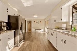A modern kitchen with white cabinetry, a stainless steel refrigerator, and a countertop with a coffee maker.