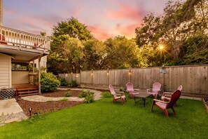 A backyard with a wooden deck, a patio table with chairs, and a wooden fence.