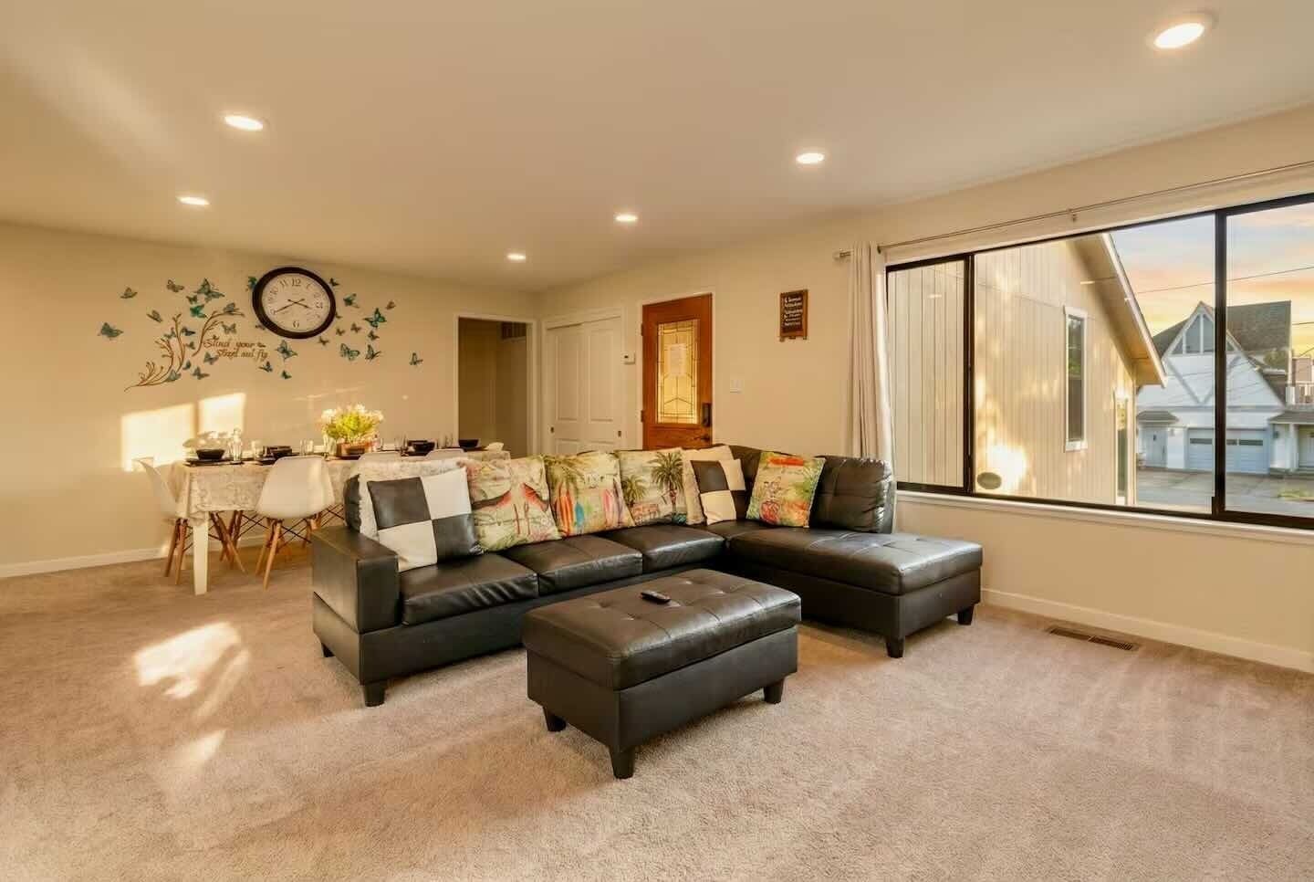Una sala de estar con un sofá modular, una mesa de comedor y un ventanal grande.