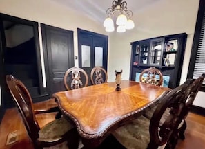 Ein Esszimmer mit einem großen Holztisch, verzierten Stühlen und einer Kronleuchter.