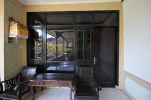 A room with a large sliding glass door, a wooden table, and two chairs. - Moanna Stay Kuta Beach (Kuta)