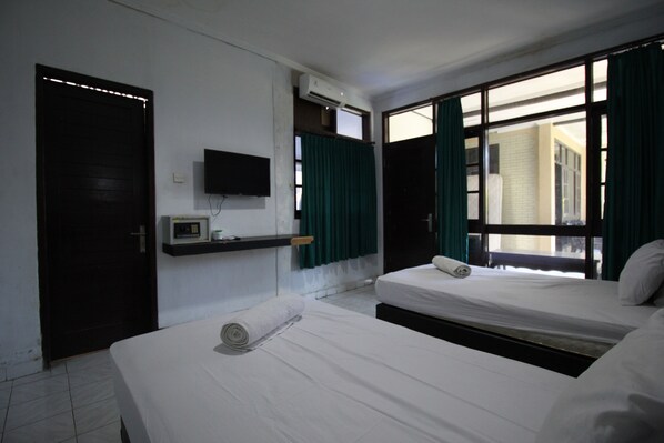 Habitación de hotel con dos camas, televisión, aire acondicionado y ventana con cortinas.