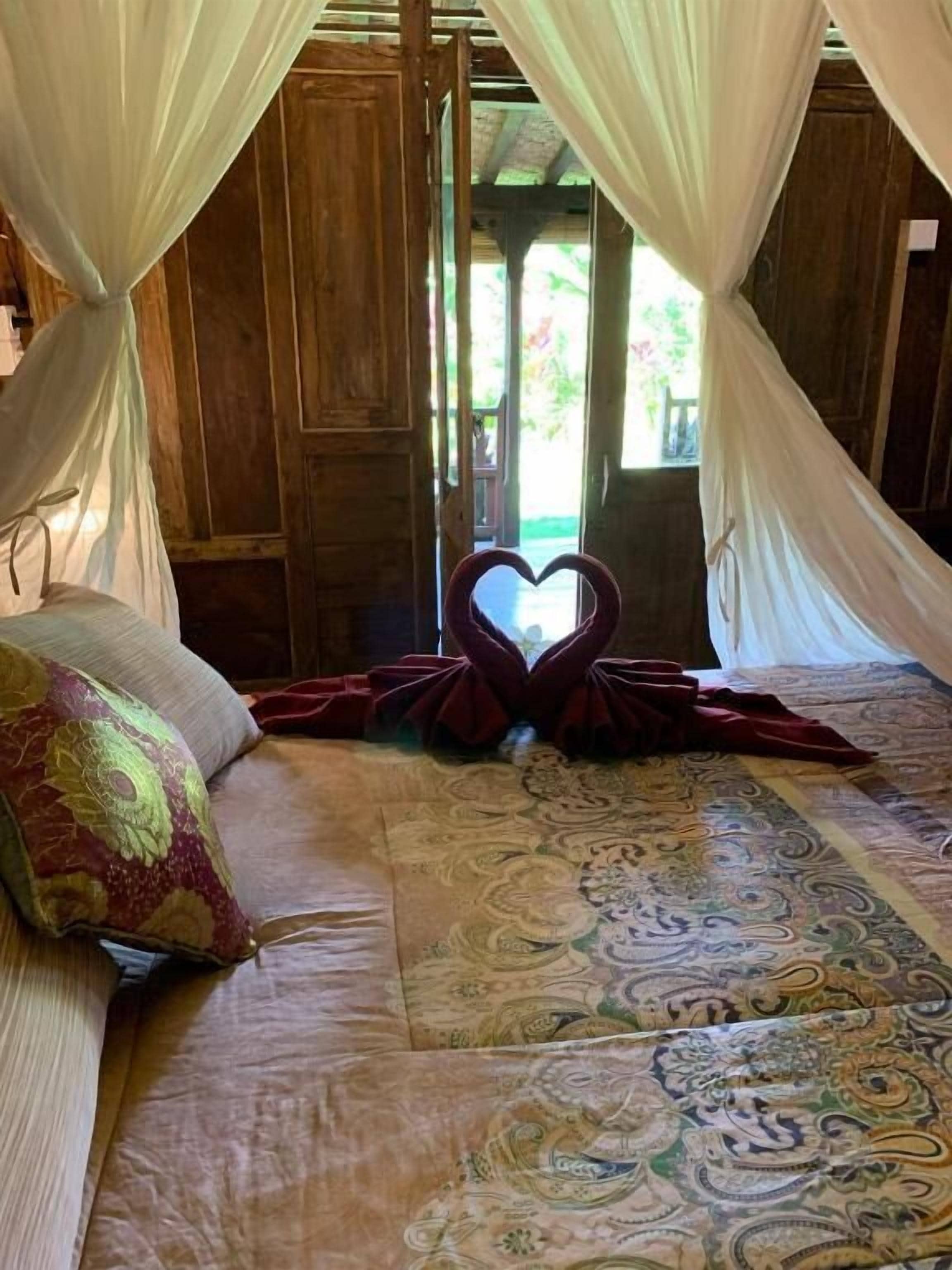 Un lit à baldaquin, une décoration en forme de cœur et une couvre-lit à motifs.