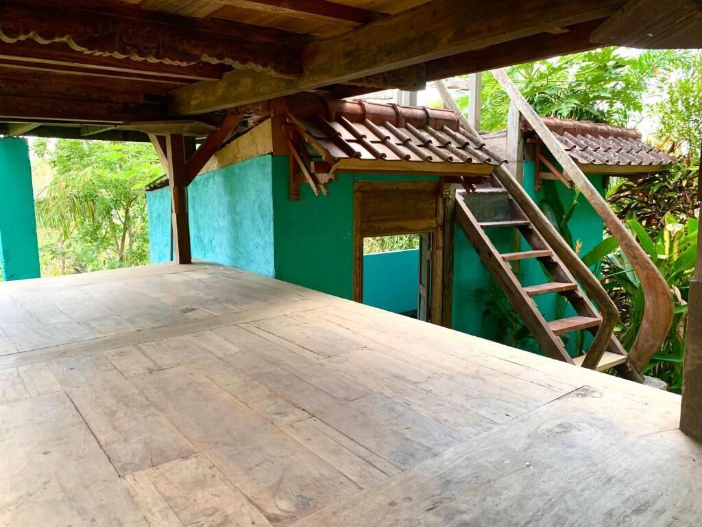 A wooden deck with a staircase leading to a covered area with a tiled roof.