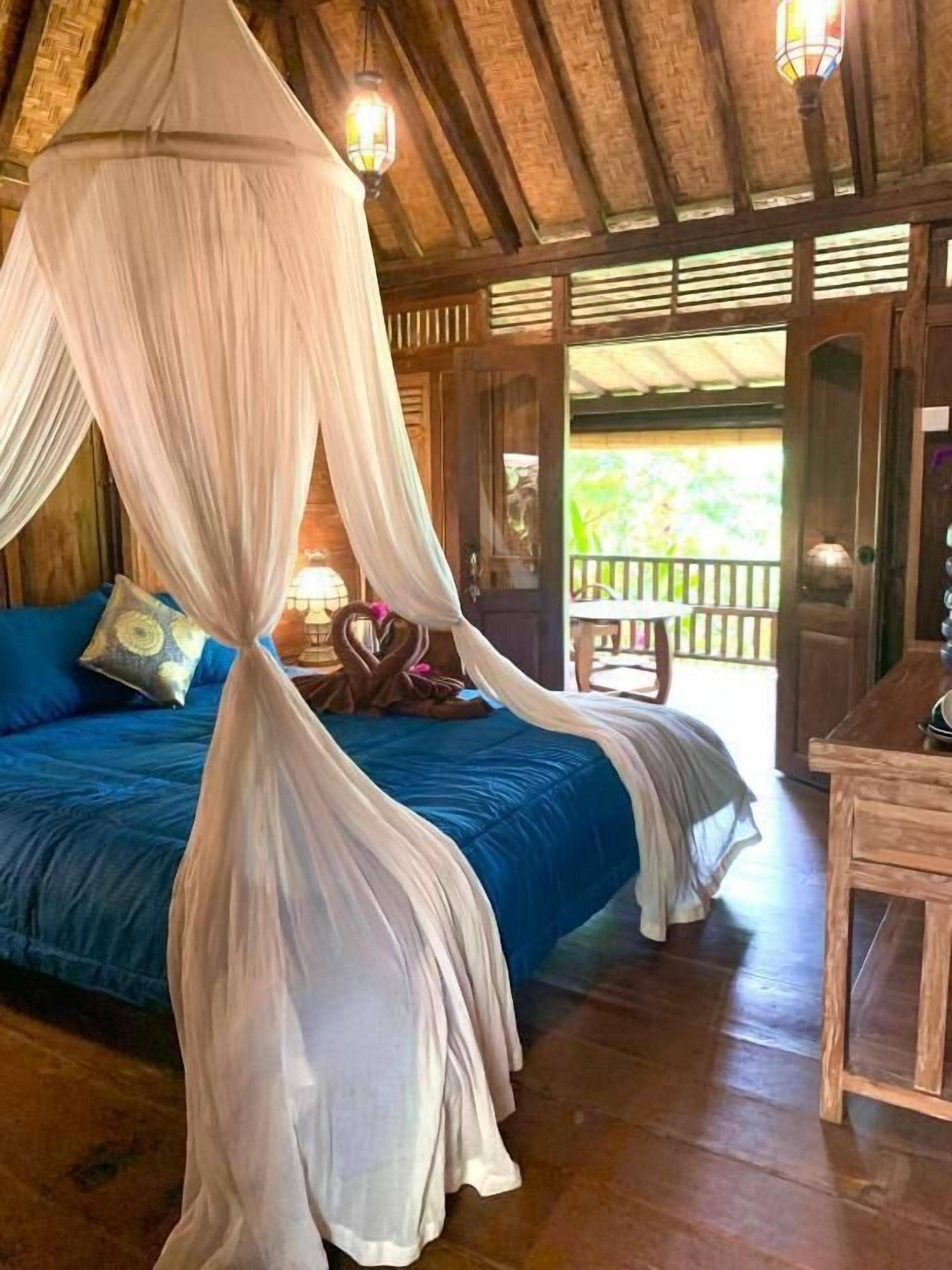 Une chambre avec un lit, une table en bois et un balcon doté d’une balustrade.