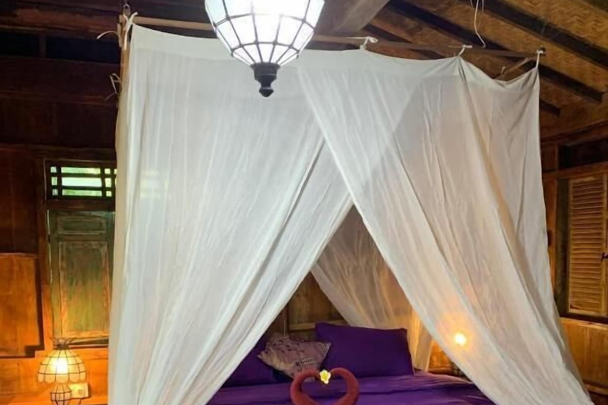 A bed with a canopy and a heart-shaped decoration on the pillows.