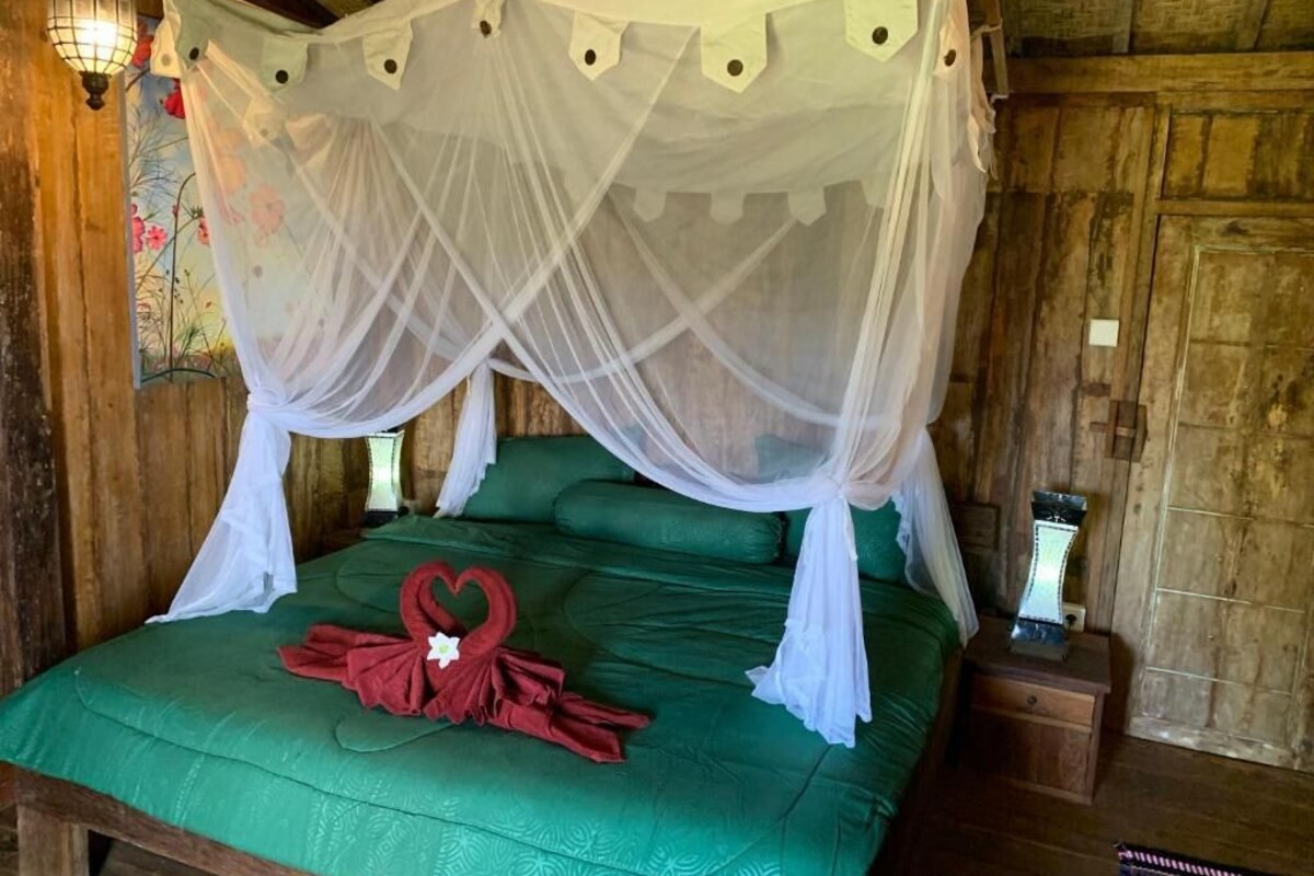 A bed with a green bedspread and a white canopy.