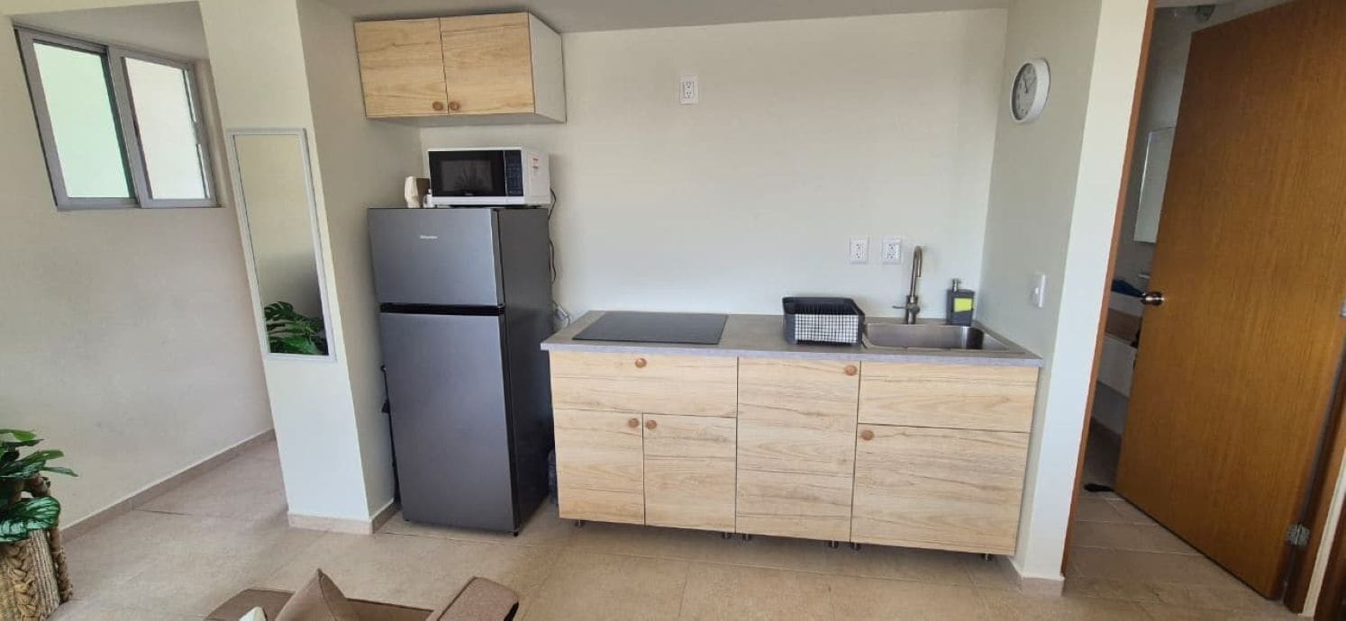A compact kitchen with a refrigerator, microwave, and wooden cabinets.