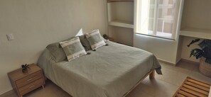 A bedroom with a bed, two nightstands, a wooden bench, a window, and a plant. - Oasis in El Chante Pool Near the Malecón (Chantepec)