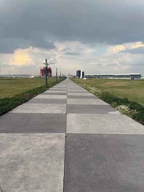 A straight pathway leading to a building with a flat roof and large windows.