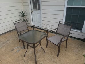 An outdoor patio with a table and two chairs, a door, and a window. - Fort Benning & Columbus, Ga - Home Away From Home (Columbus)