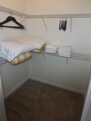 A small, neatly organized closet with hanging space, shelves, and a folded bed. - Fort Benning & Columbus, Ga - Home Away From Home (Columbus)
