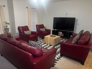 A living room with a sofa, two armchairs, a coffee table, and a flat-screen TV. - Fort Benning & Columbus, Ga - Home Away From Home (Columbus)