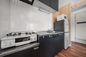 A modern kitchen with a gas stove, a microwave, and a refrigerator. - TetiTeti (Sapporo)