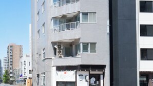 Un edificio a più piani con balconi, un ingresso a livello strada e un cielo sereno.