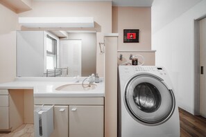 A modern bathroom with a built-in washing machine, a large mirror, and a toilet. - TetiTeti (Sapporo)