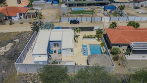 An aerial view of a residential area with a swimming pool, a covered patio, and a car parked nearby. - Private 3BR2BA Villa w/ Private Pool & Close2Beach (Noord)