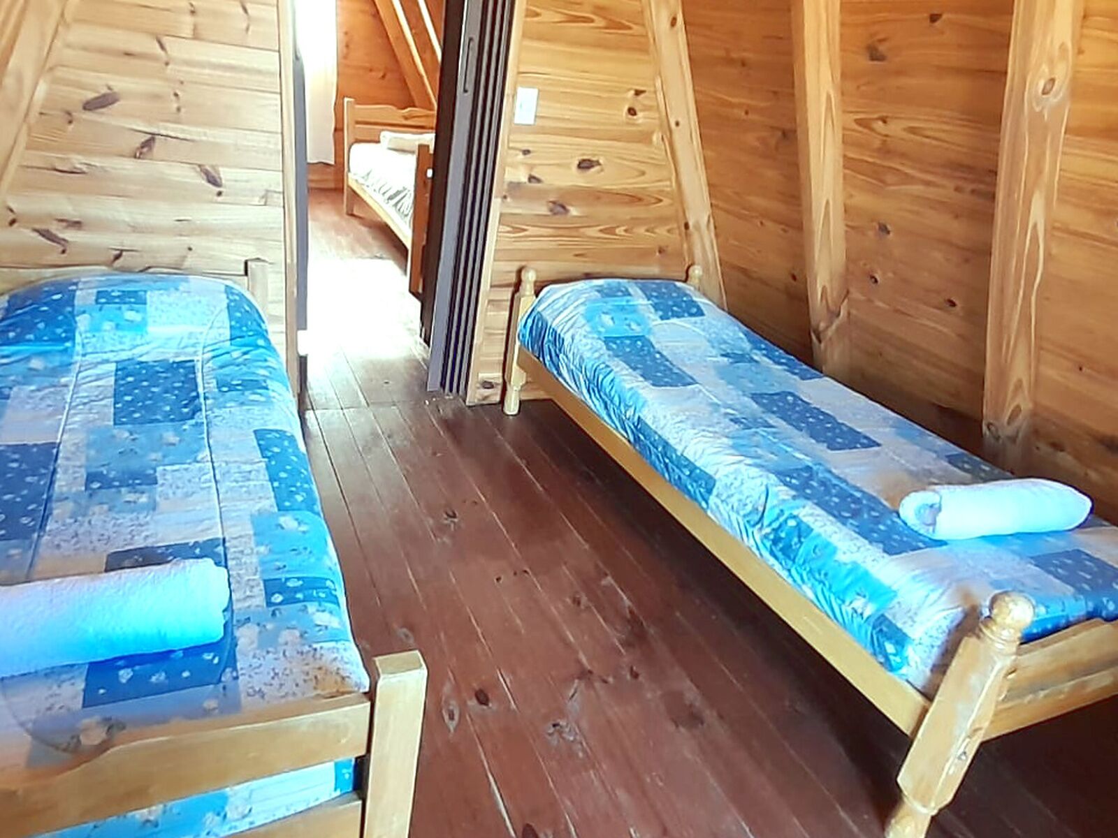 Una cabaña de madera con dos camas individuales, cada una con colcha azul.
