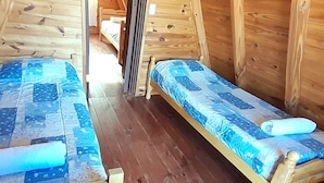Una cabana de fusta amb dos llits individuals, cadascun amb un llençol blau.