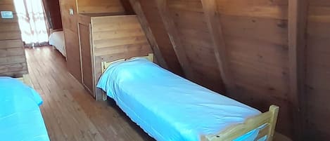 Una cama de madera sencilla en una cabaña con techo inclinado.