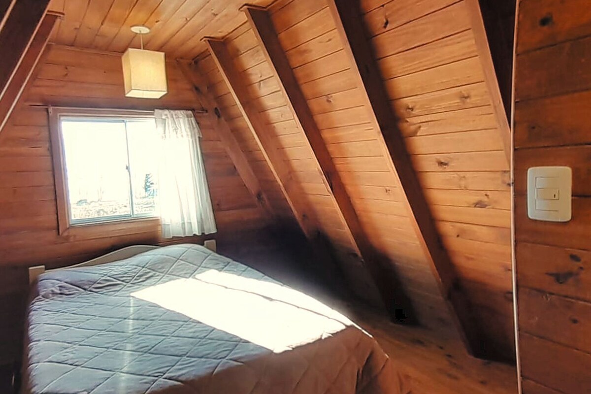 A room with a bed, a window with curtains, and a light fixture.