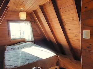 Une pièce avec un lit, une fenêtre avec des rideaux et un luminaire.