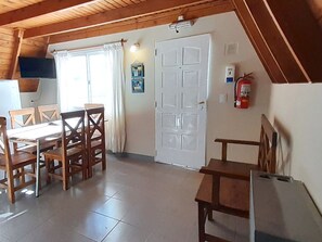 A dining area with a table and chairs, a white door, and a fire extinguisher on the wall.