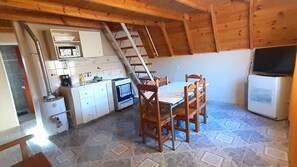 A compact kitchen with a dining table and chairs, a microwave, a stove, and a refrigerator.