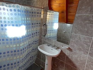 Un bany amb dutxa, un lavabo i un mirall.