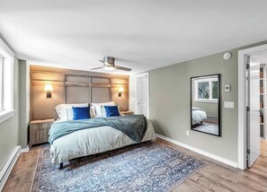 A bedroom with a bed, bedside lamps, a ceiling fan, a large mirror, and a window. - Summit View Retreat (Dover)