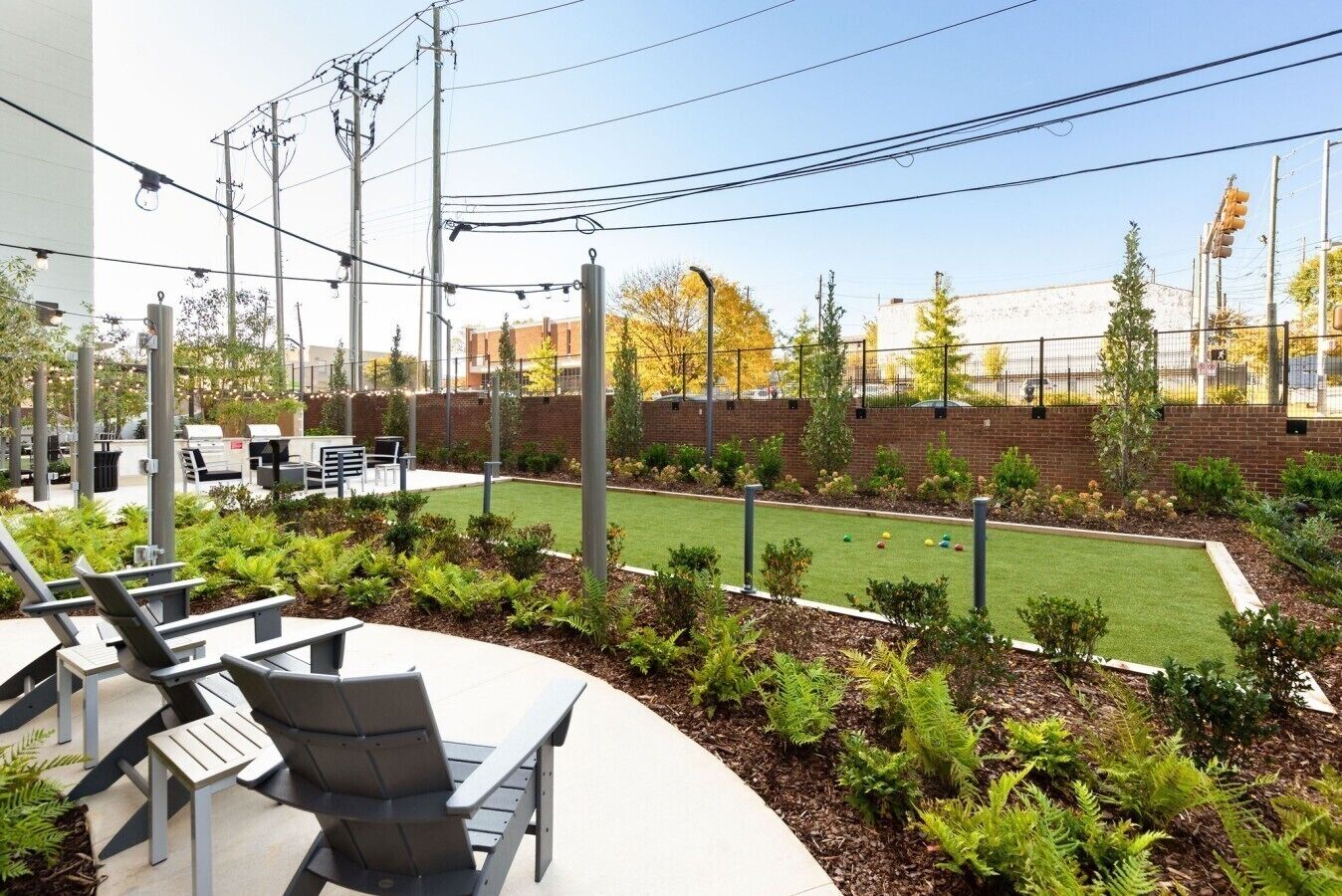 An outdoor seating area with chairs and tables, a small lawn, and a brick wall.
