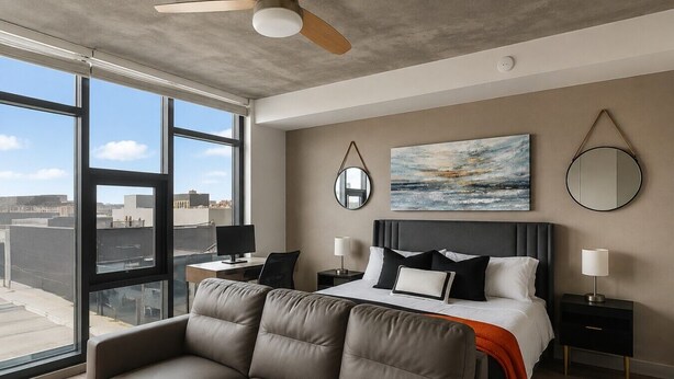 Ein modernes Hotelzimmer mit einem großen Bett, einer Couch, einem Schreibtisch und Blick auf die Stadt.