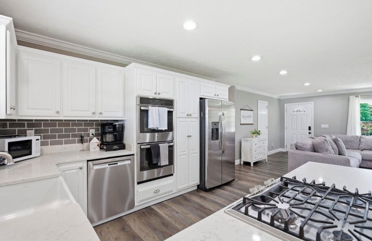 A modern kitchen with stainless steel appliances, white cabinetry, and a gas stove.