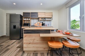 A modern kitchen with a built-in refrigerator, wooden cabinets, and a dining area with stools. - 3BR2BA Home w/Private Pool & BBQ in Great Location (Noord)