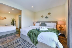 Une chambre d’hôtel avec un lit double, une table de chevet avec une lampe, un plaid vert et des œuvres d’art décoratives au mur.