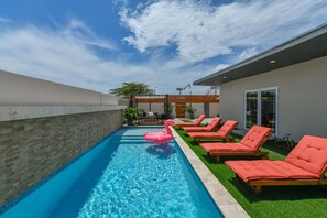 A swimming pool with lounge chairs and a pink flamingo float. - 3BR2BA Home w/Private Pool & BBQ in Great Location (Noord)