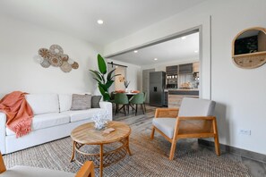 A modern living room with a sofa, armchair, and round coffee table. A dining area with chairs and a table is visible in the background. - 3BR2BA Home w/Private Pool & BBQ in Great Location (Noord)