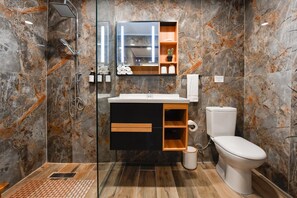 A modern bathroom with a glass-enclosed shower, a sink with a black cabinet, and a toilet. - 3BR2BA Home w/Private Pool & BBQ in Great Location (Noord)