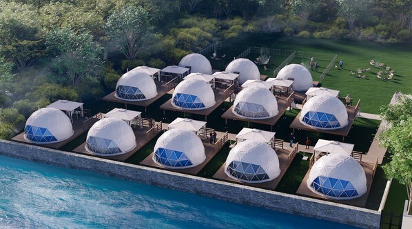 A series of dome-shaped accommodations with outdoor seating areas, surrounded by a landscaped garden and a body of water. - GLAMPREMIER Naruto (Naruto)