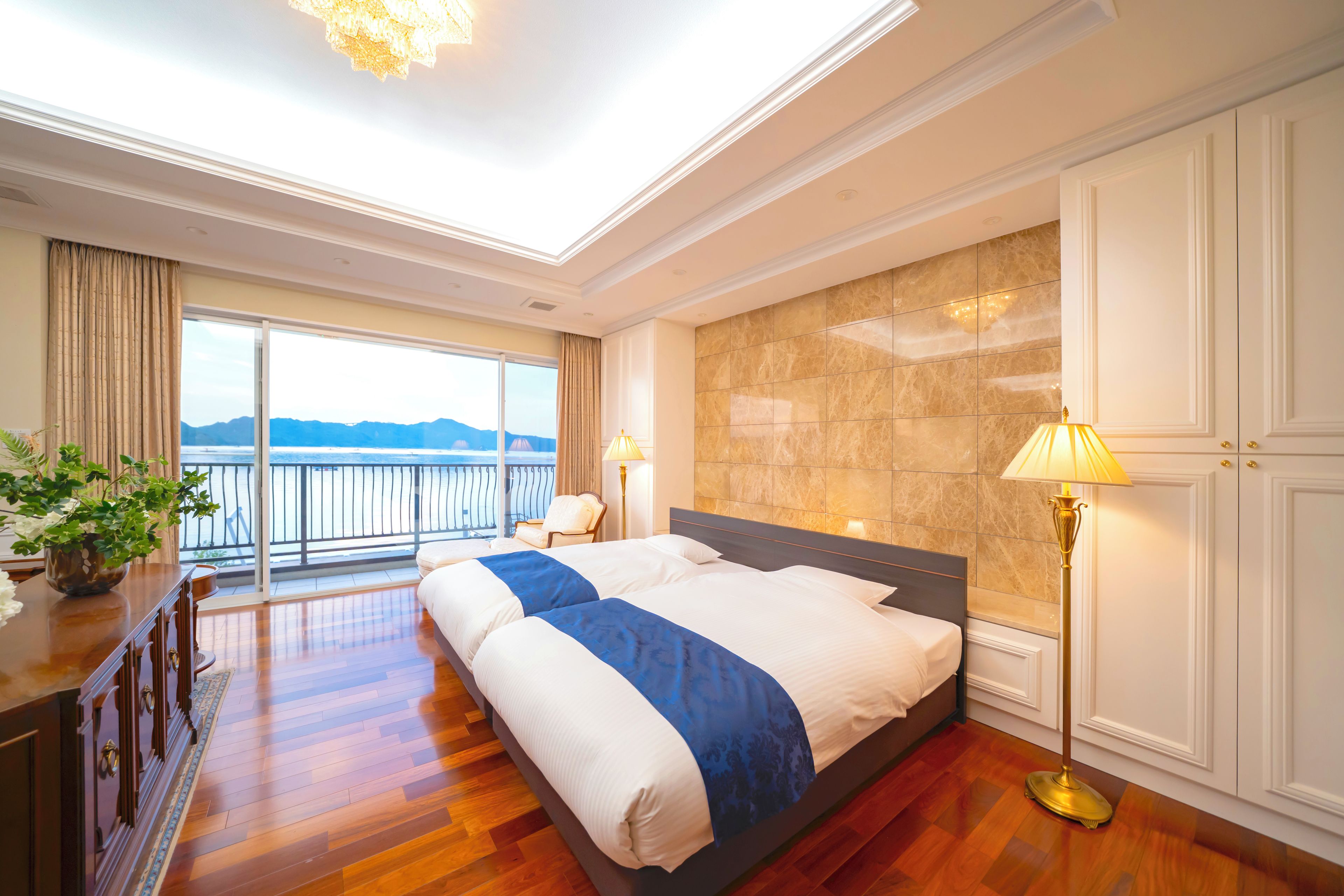 Habitación de hotel con una cama grande, un escritorio, una silla, una lámpara y vista al mar.