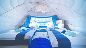 A tent-style room with two beds, a large window, and a chandelier.