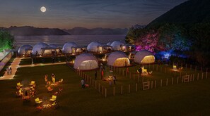 Varias tiendas en forma de cúpula dispuestas en semicírculo, con un lago y montañas al fondo.